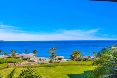 Enjoy wide ocean vistas framed by tropical trees and distant shoreline from this elevated vantage point.