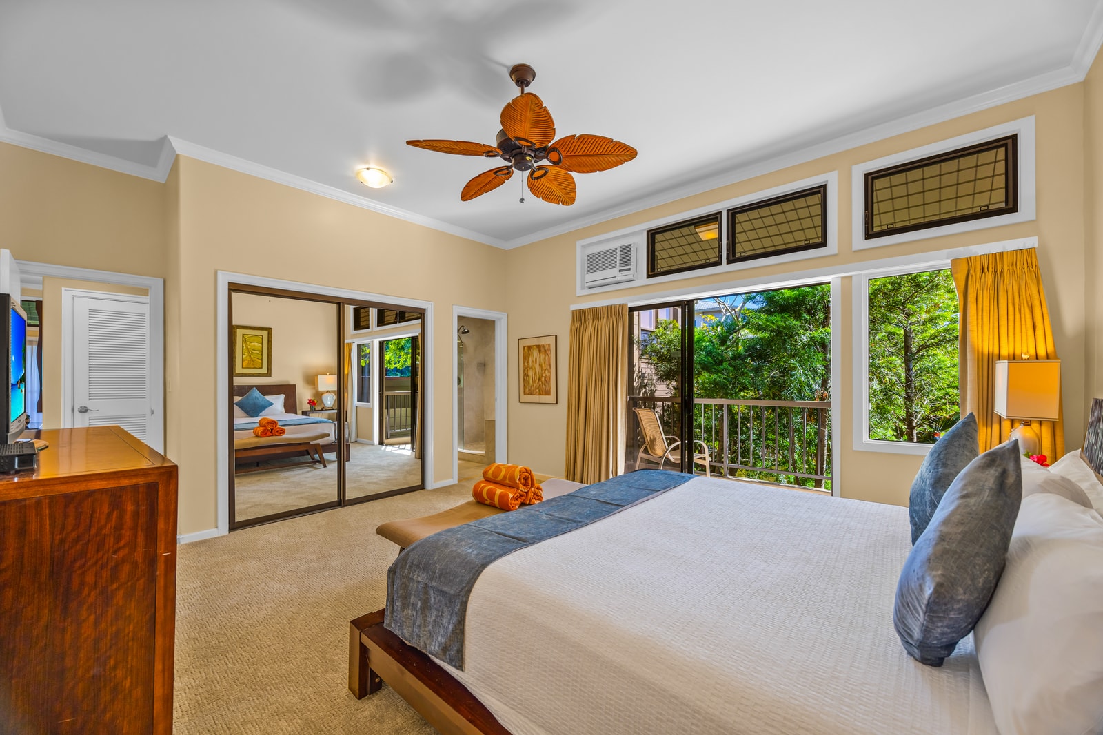 This spacious bedroom includes a Smart TV, ceiling fan, and tropical garden views.
