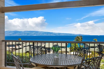 Scenic balcony dining with panoramic views of ocean and mountains.
