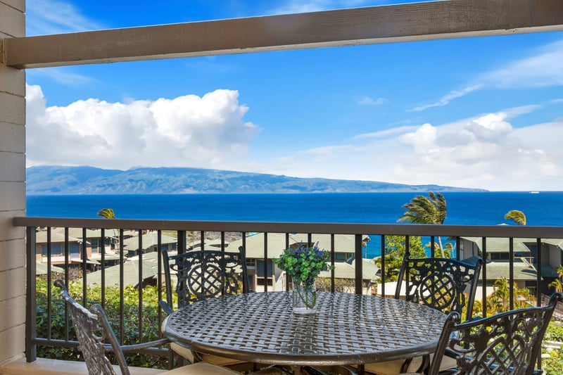 Scenic balcony dining with panoramic views of ocean and mountains.
