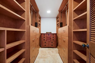 Spacious walk-in closet with custom wood shelving and storage drawers.