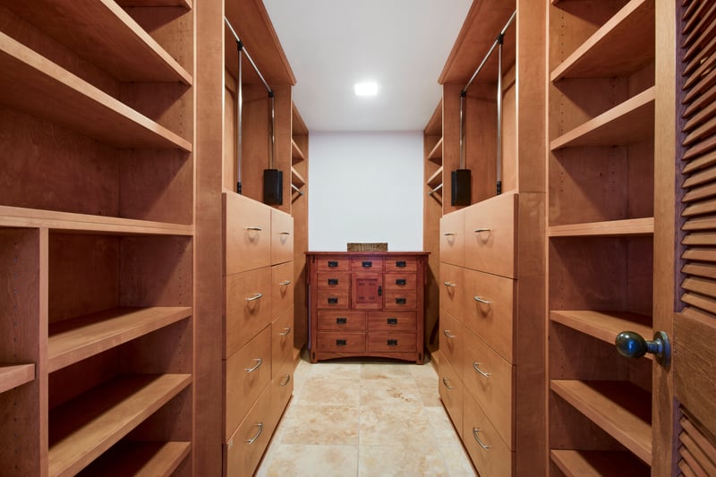 Spacious walk-in closet with custom wood shelving and storage drawers.