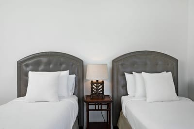 Tailored headboards, framed art, and the glow of island light create a space as graceful as it is restful