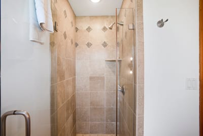 Modern walk-in shower with glass door and decorative tile accents.