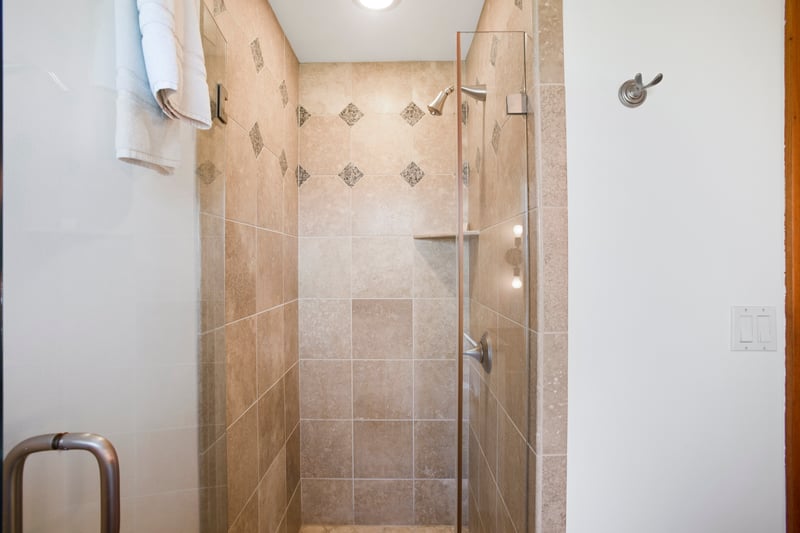 Modern walk-in shower with glass door and decorative tile accents.