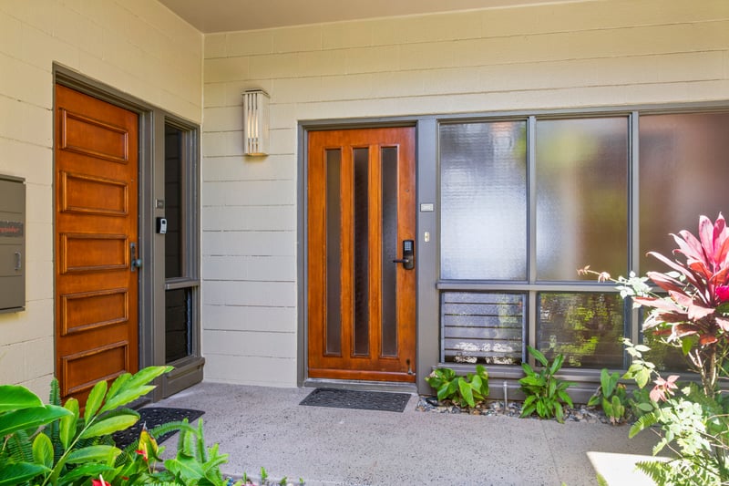 Warm wood doors and tropical foliage welcome you home in style.