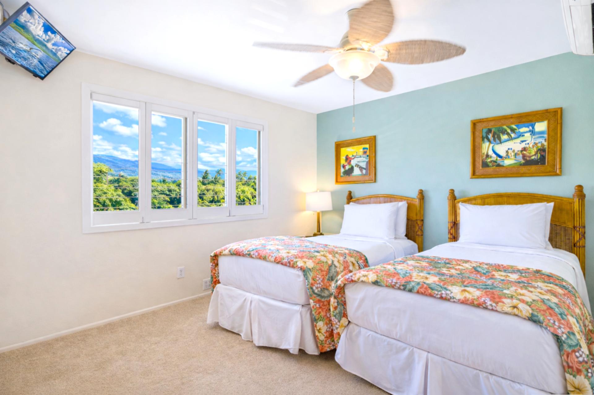 Air conditioning and tropical decor create a restful guest bedroom, with large windows welcoming in natural light.