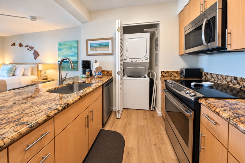 Kitchen with a stainless steel range and microwave, plus a stacked washer and dryer tucked into a closet MAH-1002
