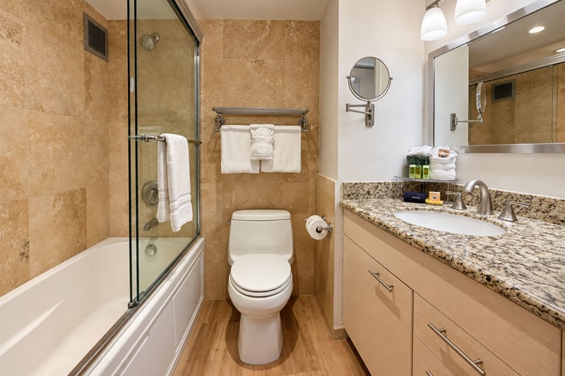Bathroom with tan stone-look tile, a tub and shower with sliding glass door, and a granite vanity with a wall-mounted mirror MAH-1002