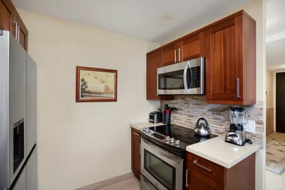 The kitchen unfolds with artisanal warmth, where polished cabinetry and ocean vistas craft a seamless symphony of form and function