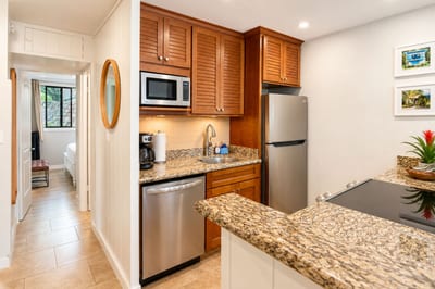 A full-size stainless refrigerator, microwave, and dishwasher anchor the well-equipped kitchen, with a peek down the hallway toward the bedroom beyond -- everything you need for easy island meals, close at hand.