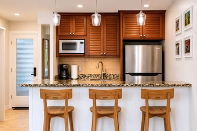 Pull up a stool at the granite breakfast bar under warm pendant lighting -- the open kitchen layout makes it easy to cook, chat, and gather with everyone.