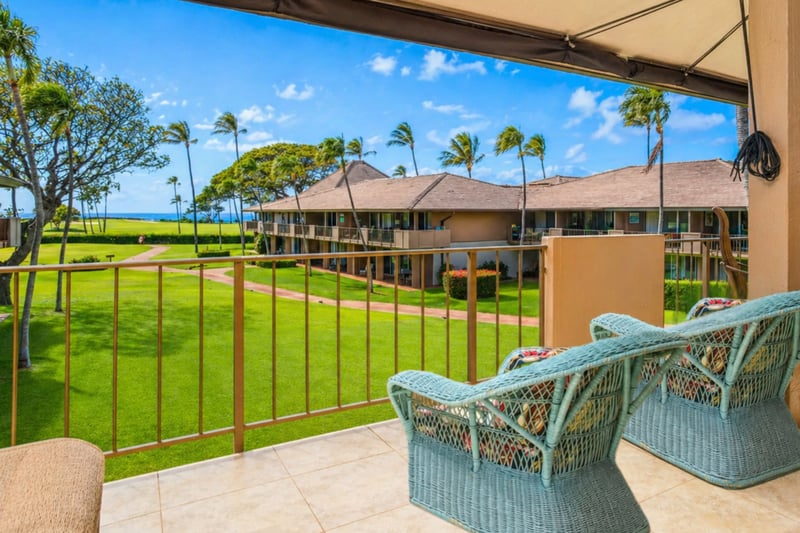Guest bedroom at Maui Eldorado H207 — two queen beds, private lanai access, and ocean-view dining table just outside