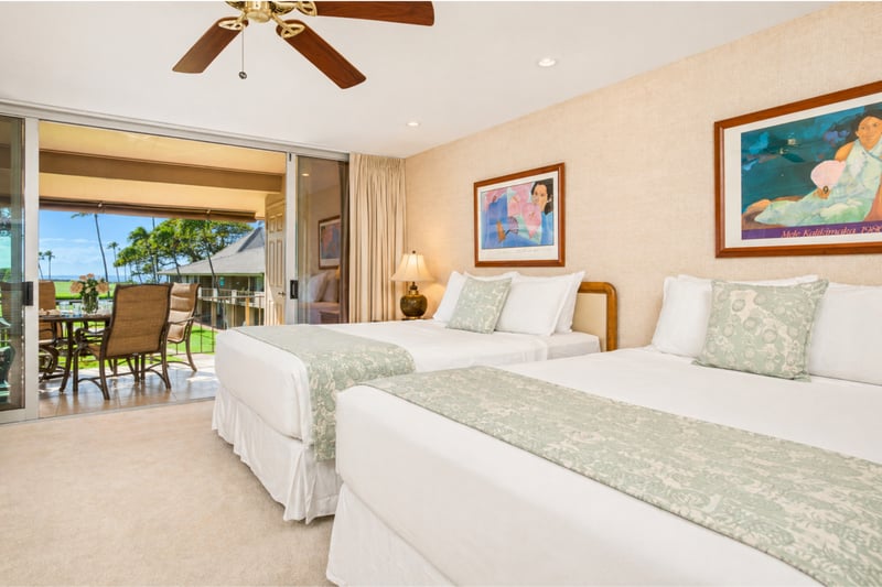 Primary bedroom at Maui Eldorado H207 — two queen beds with direct access to a furnished lanai and fairway views