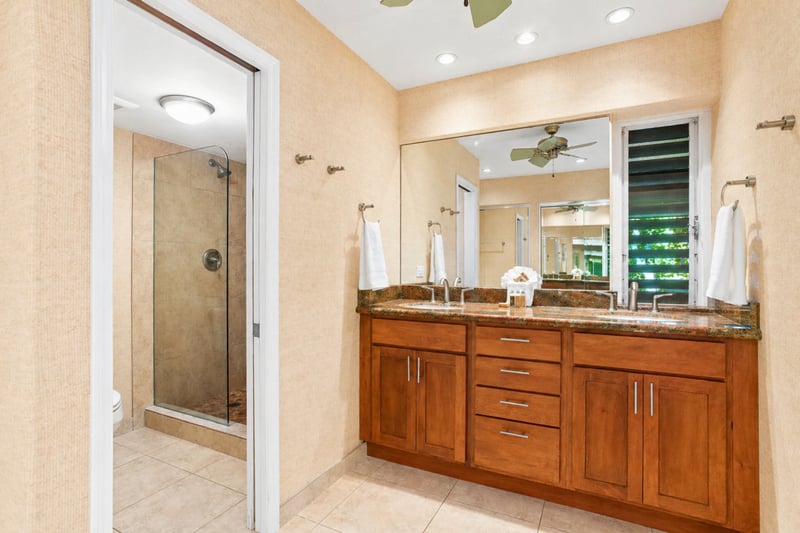 Ensuite bathroom at Maui Eldorado H207 — dual vanity with granite countertop, mirrored wall, and walk-in glass shower