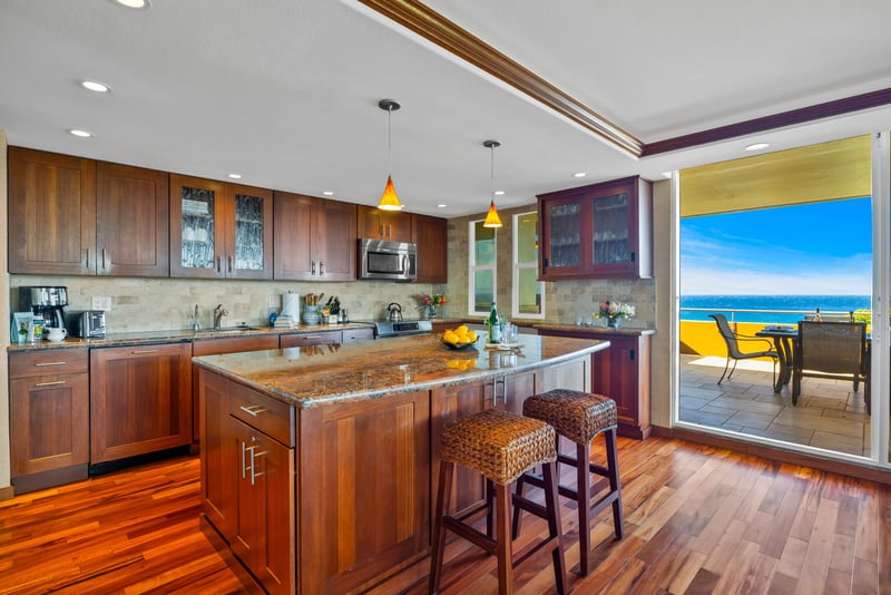 Fully equipped kitchen with stainless appliances and breakfast bar, perfect for prepping beach-day snacks.