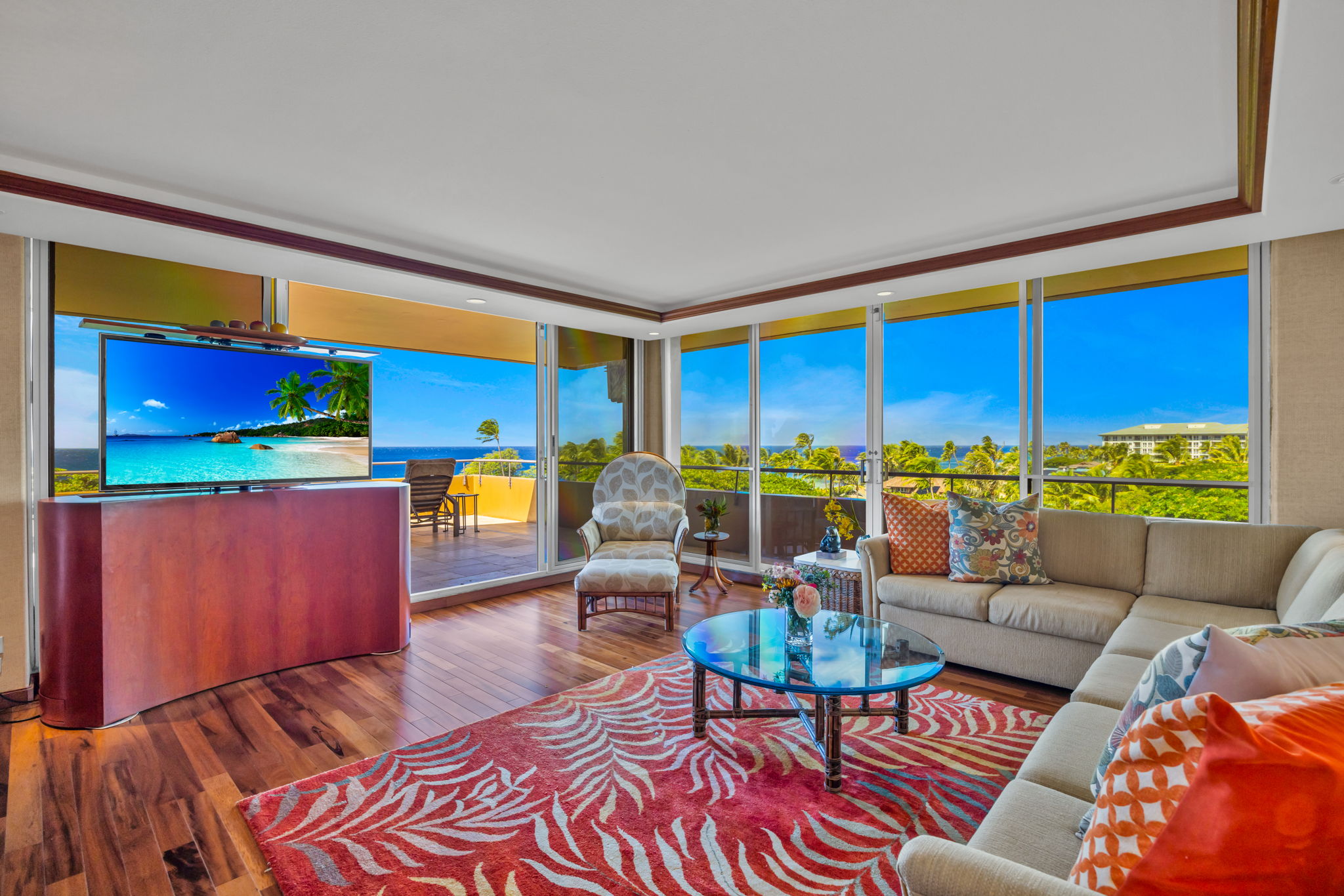 Open-concept living room with large windows that bring in natural light, sounds of the ocean, and resort greenery.