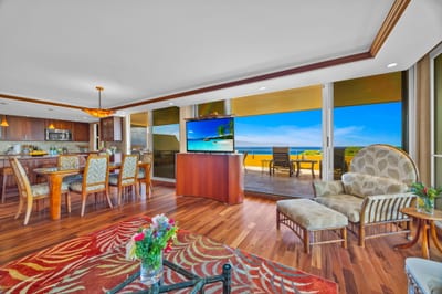 Open-concept living room with large windows that bring in natural light, sounds of the ocean, and resort greenery.