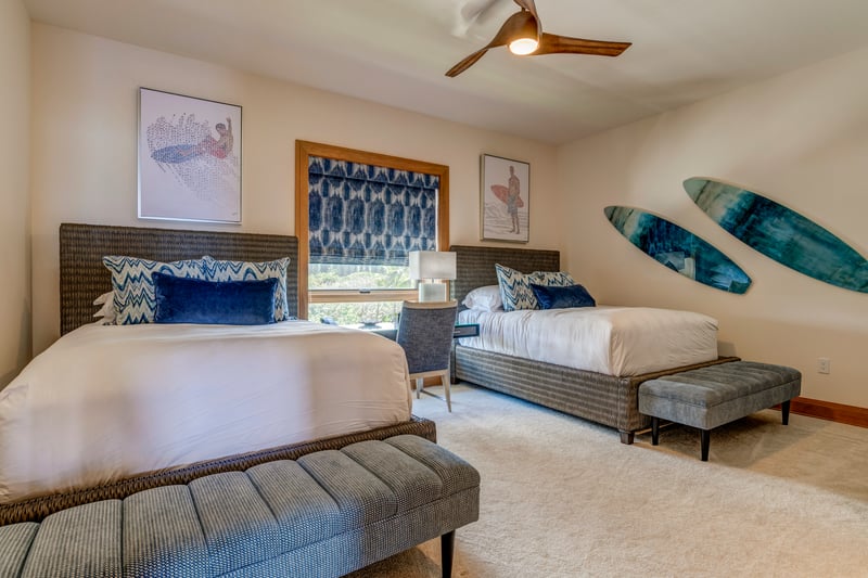 Two queen beds rest beneath surf-inspired art, blending laid-back luxury with playful, oceanic elegance