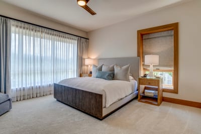 Floor-to-ceiling windows bathe the room in light, framing serene views beyond the comfort of the king bed