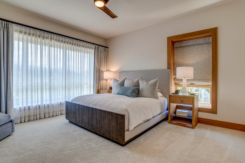 Floor-to-ceiling windows bathe the room in light, framing serene views beyond the comfort of the king bed