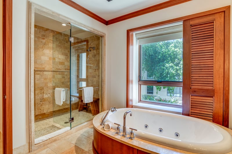 The glass shower gleams with timeless stonework, inviting you into a serene space where stress simply dissolves    