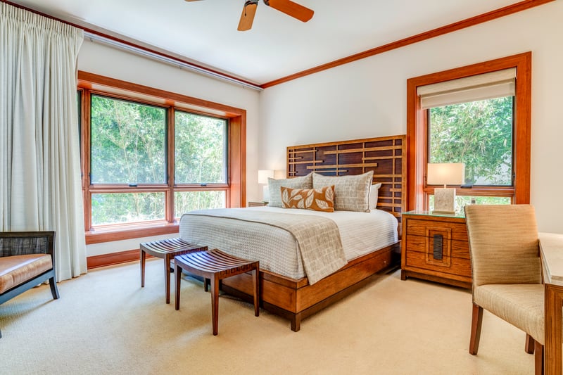 Natural light pours through generous windows, framing a bed that beckons with quiet comfort and calm views    