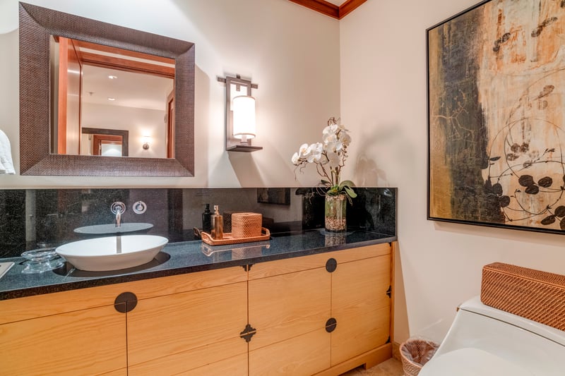 Earthy wood tones, soft lighting, and modern artwork create a bathroom experience that’s refined yet welcoming    