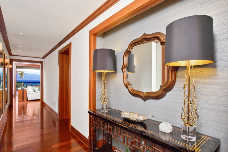 An artful hallway framed by warm woods, designer lighting, and coastal glimpses—where luxury greets you at the door   