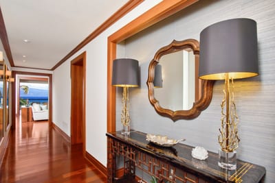 An artful hallway framed by warm woods, designer lighting, and coastal glimpses—where luxury greets you at the door