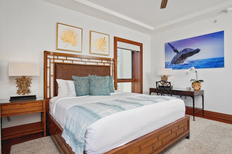 A stately king bed with a handcrafted wood frame sits center stage, flanked by coastal-inspired nightstands and art   