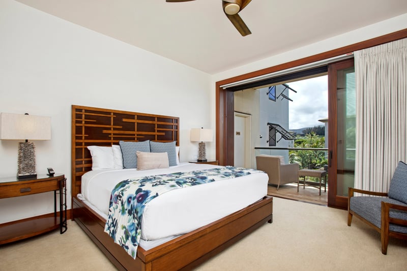The lanai offers sweeping views of tropical rooftops and lush greenery beneath a canvas of blue sky and drifting clouds   
