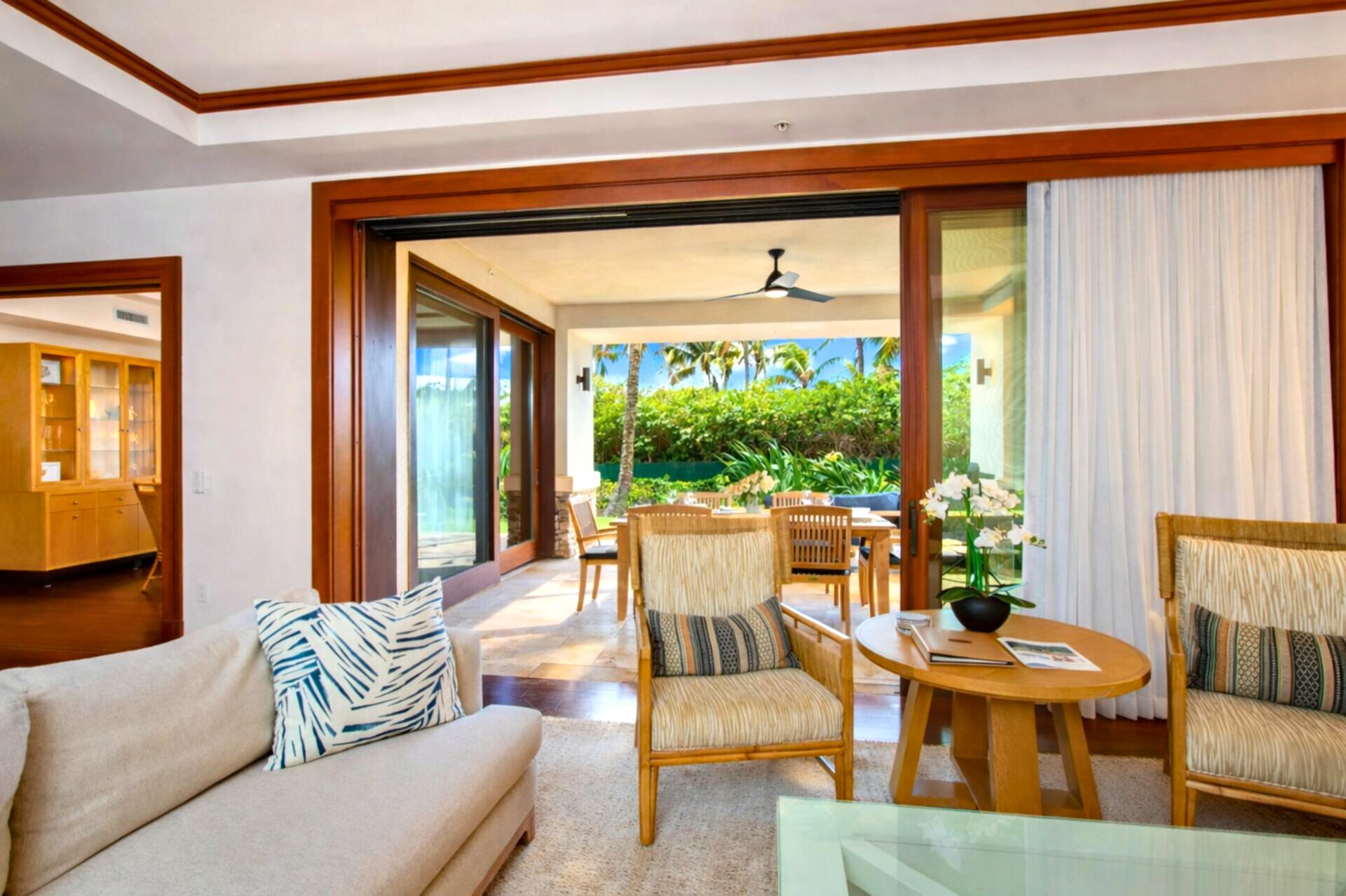 Warm wood trim and coffered ceilings frame your open living space, with direct access to the lanai and ocean beyond.