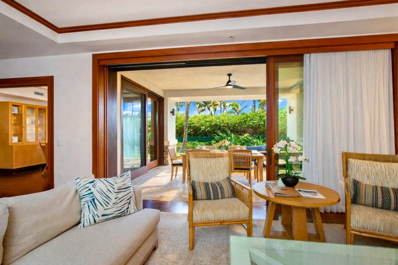 Warm wood trim and coffered ceilings frame your open living space, with direct access to the lanai and ocean beyond. MON-2204