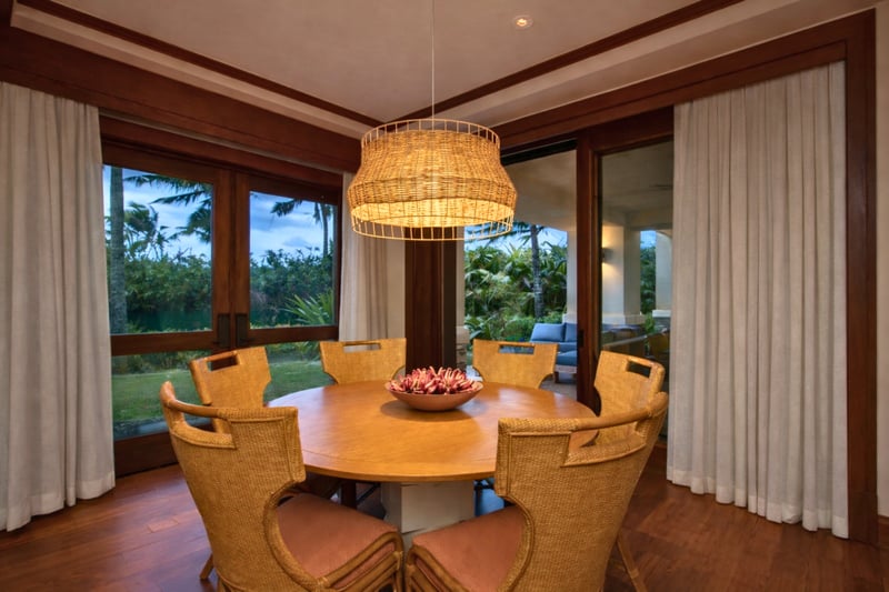 A round wood dining table sits beneath a statement chandelier, creating an inviting space for shared meals and conversation. MON-2204