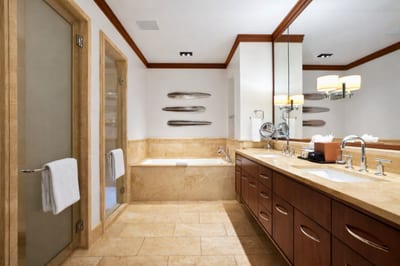 Soft neutral tones and tropical views create a restful guest retreat with easy access to the nearby bath.