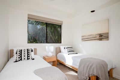 This guest retreat pairs minimal charm with warm wood, plush throws, and pillow-perfect twin beds
