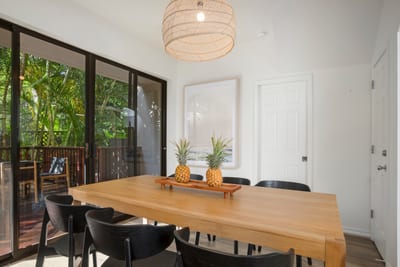 Elegant simplicity meets tropical beauty in this open dining space framed by windows and modern natural finishes