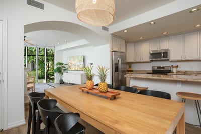 This spacious dining area offers a natural wood table, breezy openness, and a lush backdrop for any gathering