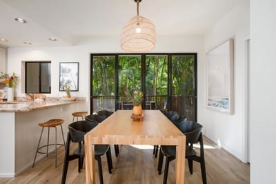 Dine under a soft pendant glow at this spacious, modern table with views of swaying palms and open sky beyond