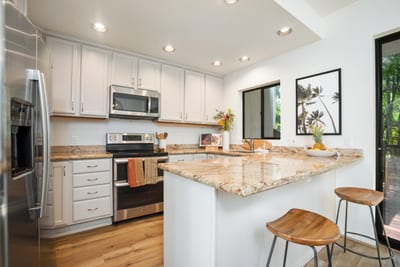 Cook and connect in a bright, refined kitchen with custom cabinetry, elegant finishes, and bar seating for two