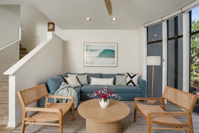 Natural light pours in through glass panels, casting warmth on soft textures and artfully arranged seating nooks
