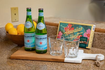 A sweet island welcome—refresh with chilled sparkling water and indulge in local chocolate-covered aloha NAP-A25