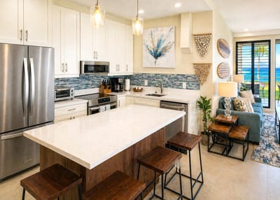 A clean white kitchen with stainless appliances, generous counter space, and a breakfast bar for casual meals