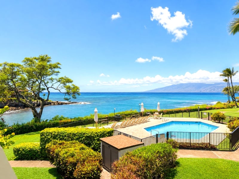 Gated oceanfront pool area surrounded by vibrant greenery