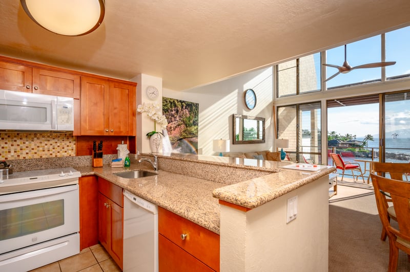 This cheerful kitchen features honey-toned wood cabinets, granite counters, and a breezy open view to the lanai NAP-C18