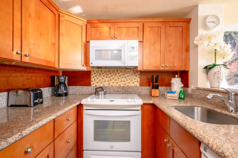 Cook with ease in this sunlit kitchen with granite countertops, full appliances, and tropical-inspired accents NAP-C18