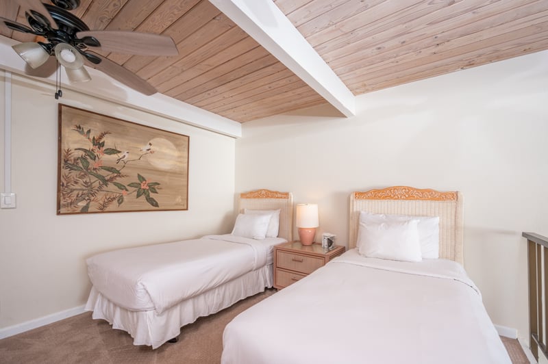 Lofted twin guest room with wood beam ceilings, oceanview balcony rail, soft lighting, and peaceful beach decor  NAP-C18