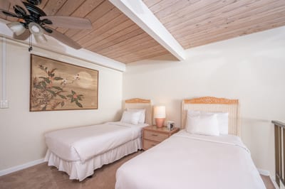 Lofted twin guest room with wood beam ceilings, oceanview balcony rail, soft lighting, and peaceful beach decor NAP-C18