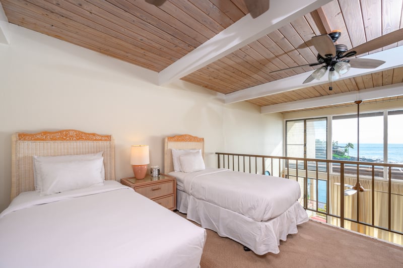 Twin guest loft with vaulted wood ceilings, tropical accents, large windows, and views of blue skies and palms   NAP-C18